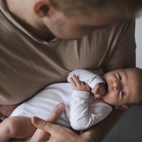 Caucasian thirty year old blond man holding newborn little baby looking at camera. Father and child relationship,love,care concept.High angle view.. licença-paternidade; recém-nascido; bebê. Crédito: Freepik